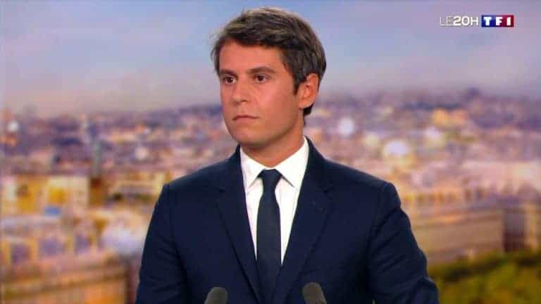 Un homme en costume et cravate parlant dans un microphone en français.