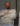 Homme assis, regard pensif, vêtements clairs.