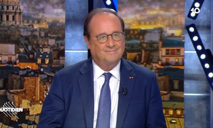 Homme souriant en interview avec décor urbain.