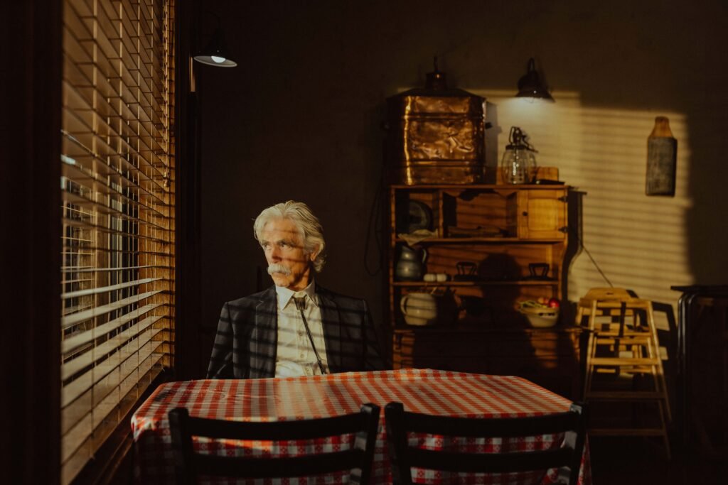 Homme âgé assis à une table, lumière douce.