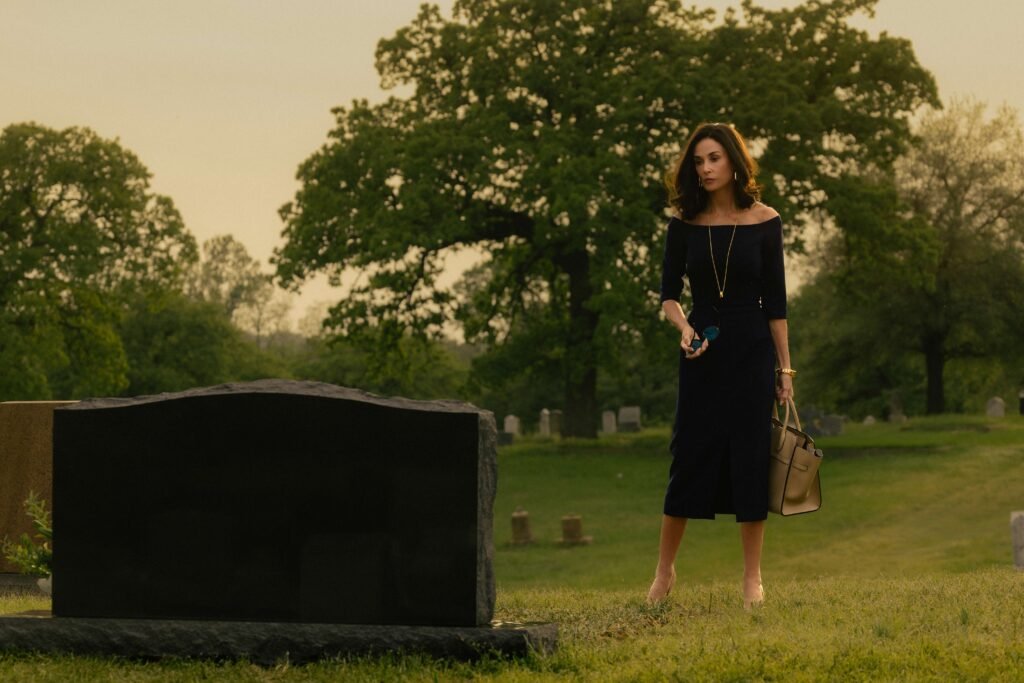 Femme en noir se tenant près d'une tombe.