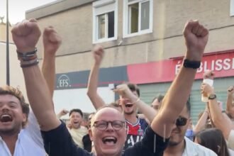 Édouard Philippe bras levés célèbre la victoire du PSG en Ligue des champions entouré de supporters