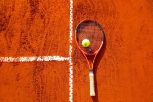 Raquette et balle de tennis sur terre battue rouge — Roland-Garros 2026