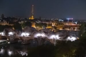 La Caverne du Pont Neuf de JR vue de nuit avec la Tour Eiffel en arrière-plan