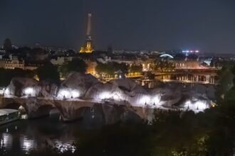 La Caverne du Pont Neuf de JR vue de nuit avec la Tour Eiffel en arrière-plan