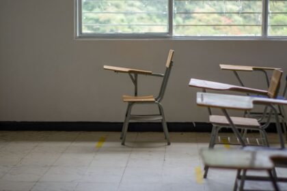Salle de classe vide avec tables d’écolier près d’une grande fenêtre