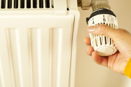 Main réglant le robinet thermostatique d'un radiateur