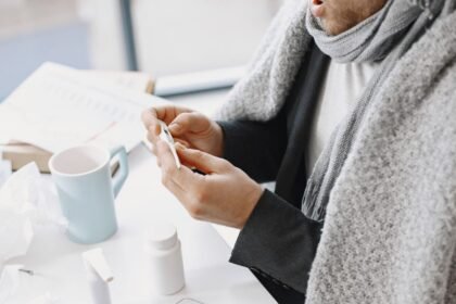Salarié enveloppé dans une couverture vérifiant sa température pendant un arrêt maladie