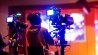 Opérateur de caméra filmé de dos dans un studio de télévision