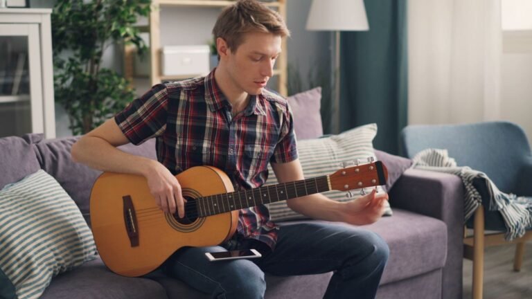 Félix star academy : 18 ans, québécois, nommé avec khalil et mélina Jeune homme jouant de la guitare acoustique sur un canapé