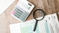 Calculatrice et loupe posées sur des documents fiscaux