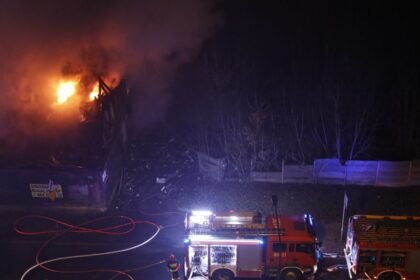 Pompiers et engins devant un bâtiment en feu, de nuit