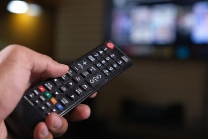 Personne tenant une télécommande devant un écran de télévision flou