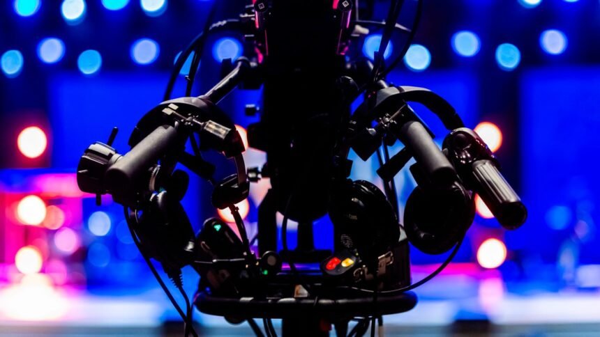 Salaire de léa salamé : france 2 dit avoir supprimé la part liée au 20 heures Silhouette d’une caméra de télévision devant des projecteurs de studio