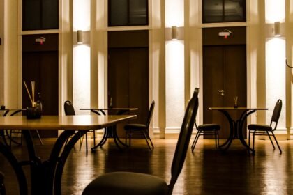 Salle de restaurant vide éclairée, chaises et tables en bois