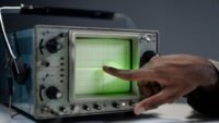 Séisme à ambert : la magnitude 3,6 confirmée, des secousses depuis le 16 octobre Main pointant l'écran d'un oscilloscope ancien, illustration de relevés de secousses