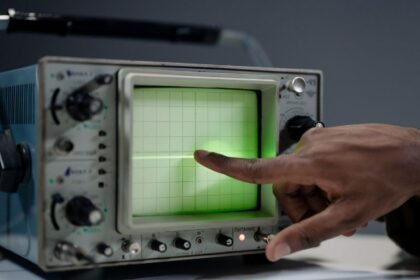 Main pointant l'écran d'un oscilloscope ancien, illustration de relevés de secousses