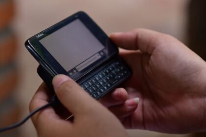 Mains tenant un ancien téléphone portable à clavier, de type 2G