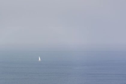 Un voilier navigue seul sur un océan brumeux