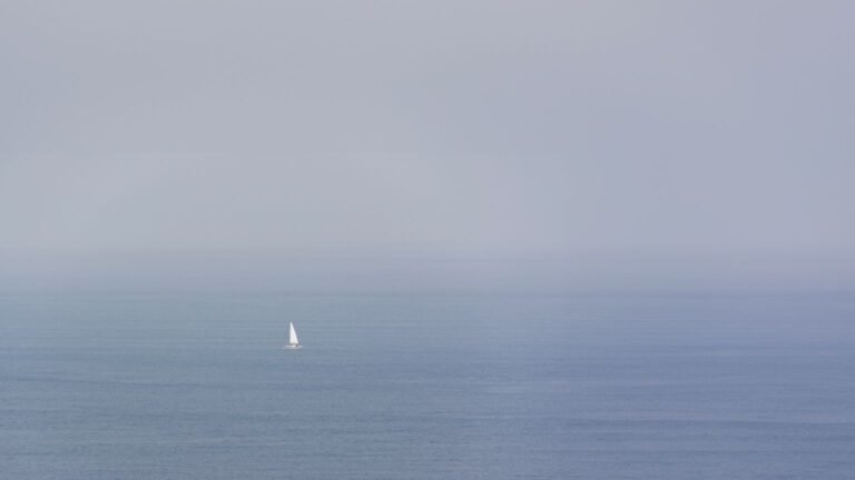 Un voilier navigue seul sur un océan brumeux
